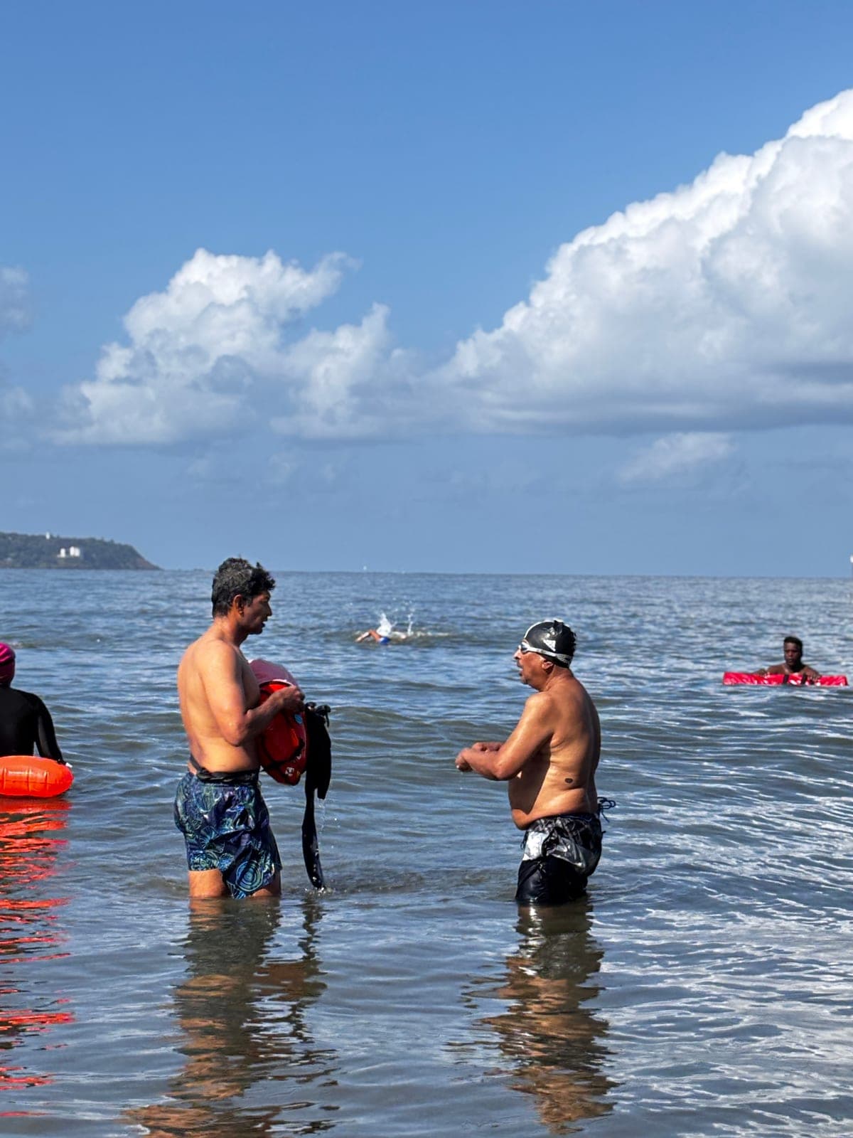 Two swimmers chatting in the sea under towering clouds
