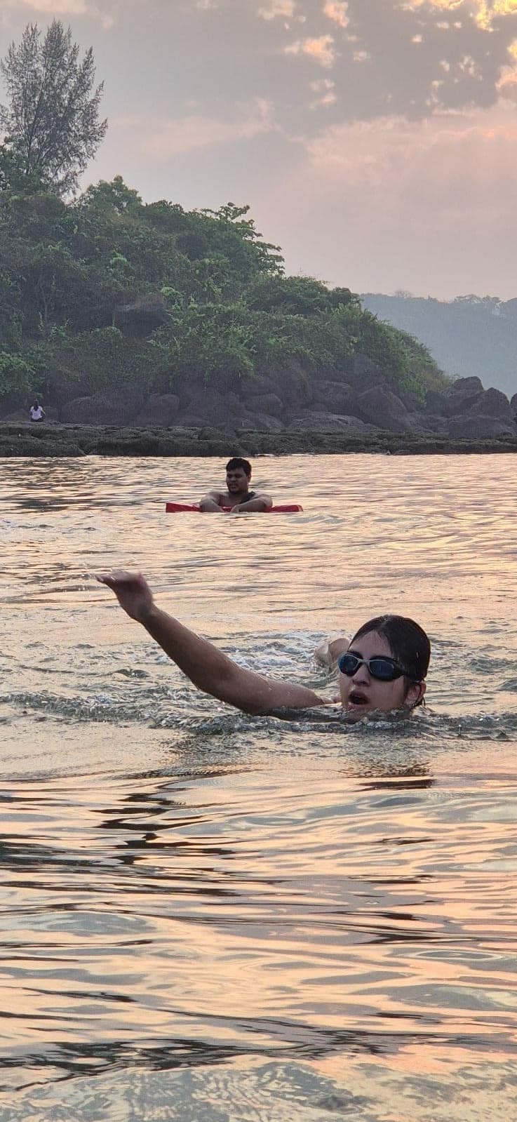 Swimmer doing freestyle in the sea under a pink sunset sky