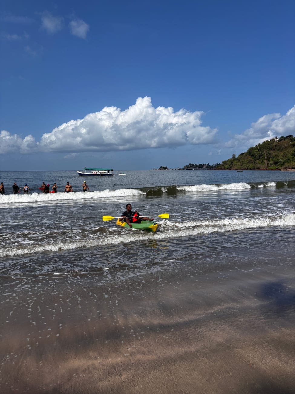 A swimmer paddling a kayak in the surf at Dona Paula