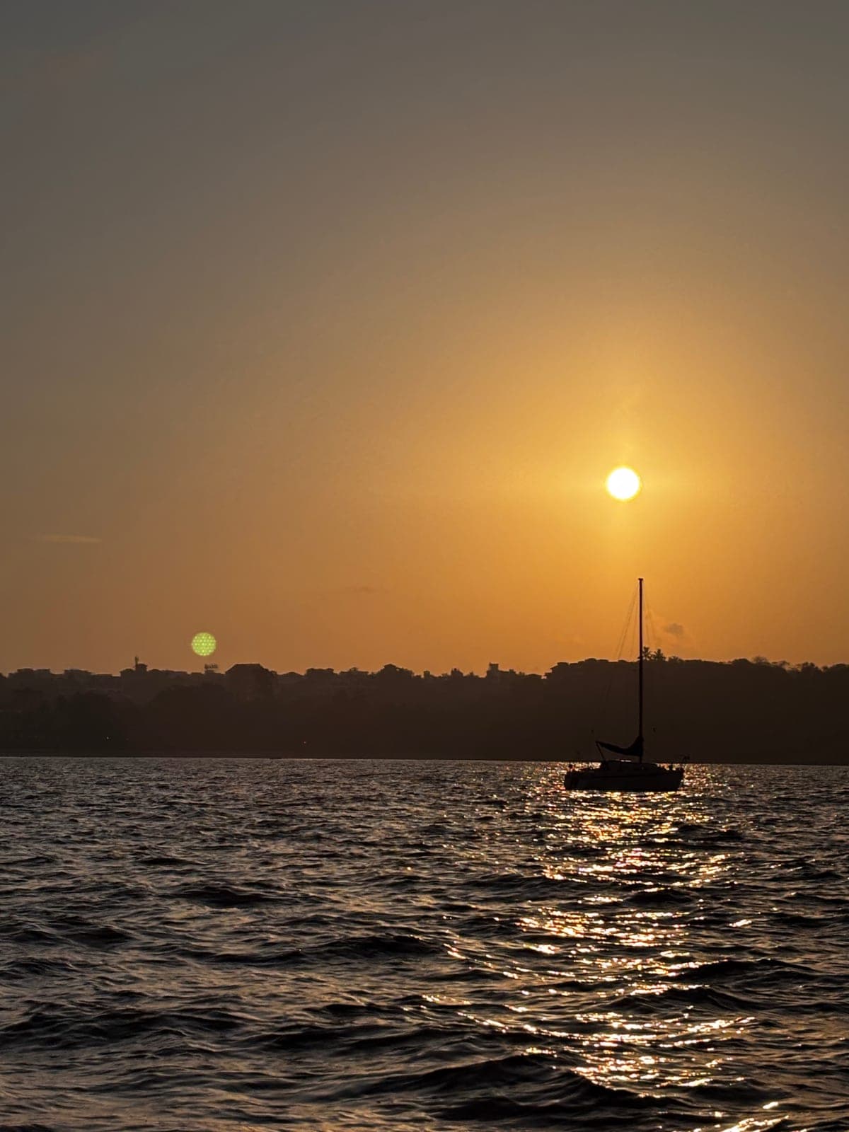 A sailboat silhouetted against a golden sunset off Dona Paula, Goa